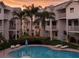 Exterior shot of condo community pool, palm trees, and lush green landscaping at sunset at 125 Shoals Cir, North Redington Beach, FL 33708