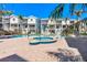 Community spa and swimming pool with white beach homes, lounge chairs and palm trees at 125 Shoals Cir, North Redington Beach, FL 33708