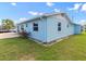 Side exterior view of a light blue single-story home showcasing windows, greenery, and a paved patio at 13437 Lisa Dr, Hudson, FL 34667