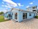Rear exterior view of a single-story light blue home featuring sliding glass doors and paved patio at 13437 Lisa Dr, Hudson, FL 34667