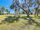 A beautiful open lawn area surrounded by mature trees on a sunny day provides a serene park-like setting at 13542 Norman Cir, Hudson, FL 34669