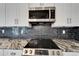 Close-up of the modern glass stovetop on granite countertops with stainless steel microwave above it at 1425 Monte Lake Dr, Valrico, FL 33596