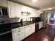 A modern kitchen featuring white cabinets, black countertops, and stainless steel appliances at 1706 E Annie St, Tampa, FL 33612