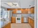 Kitchen with stainless steel appliances, white countertops and backsplash, and wood cabinets at 19029 Us Highway 19 N # 17A, Clearwater, FL 33764