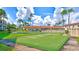 Community putting green surrounded by lush grass, mature palm trees, and residential buildings under a bright sky at 19029 Us Highway 19 N # 17A, Clearwater, FL 33764