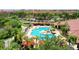Aerial view of a pool area with cabanas, lounge chairs, and lush landscaping in a red-roofed community at 2773 Via Cipriani # 1330B, Clearwater, FL 33764