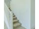 A staircase with beige carpet and white banister going up the side of a white wall at 32684 Tamarind Grove Ln, Wesley Chapel, FL 33543