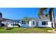 The bright white house has impact windows and mature palms at 3506 Moog Rd, Holiday, FL 34691
