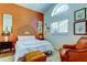 Stylish bedroom with a large window, orange accent wall, and comfortable seating area at 4967 162Nd N Ave, Clearwater, FL 33760