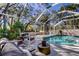 Tranquil pool area featuring an enclosed screened lanai, outdoor seating, and lush foliage at 4967 162Nd N Ave, Clearwater, FL 33760