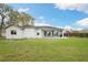 View of the home's backyard featuring a covered patio with furniture and a well-maintained lawn at 6140 Silver Oaks Dr, Zephyrhills, FL 33542