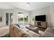 Bright living room showing hardwood floors, sliding doors to backyard, TV, and sofa at 6140 Silver Oaks Dr, Zephyrhills, FL 33542