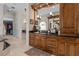 Bathroom featuring dark countertops, wood cabinets, and framed mirrors with sconces, leading to a walk-in closet at 7986 9Th S Ave, St Petersburg, FL 33707