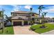 Stately yellow home boasts a tile roof, lush landscaping, and a brick driveway on a sunny day at 7986 9Th S Ave, St Petersburg, FL 33707