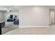 Bright living room with neutral walls and tile flooring flowing into a carpeted seating area with a large TV at 8034 Broad Pointe Dr, Zephyrhills, FL 33540
