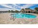 A large pool with clear blue water, surrounded by deck chairs and lush landscaping at 8034 Broad Pointe Dr, Zephyrhills, FL 33540