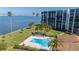 Aerial view of pool near beachfront condo with palm trees and clear blue water at 100 Oakmont Ln # 112, Belleair, FL 33756