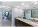 Bright bathroom featuring double sinks, granite counters, wood cabinets, and an open view to a bedroom at 100 Oakmont Ln # 112, Belleair, FL 33756