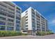 Exterior shot of condo building, showcasing private balconies and lush green landscaping at 100 Oakmont Ln # 112, Belleair, FL 33756