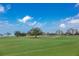 Expansive green golf course with trees, sand traps, and condo buildings on the horizon at 100 Oakmont Ln # 112, Belleair, FL 33756