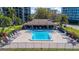 Aerial view of community pool with chairs and umbrellas, surrounded by condo buildings and lush landscaping at 100 Oakmont Ln # 112, Belleair, FL 33756