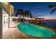 Twilight view of a backyard with a pool, dock, and lush landscaping, perfect for evening relaxation at 119 Carlyle Cir, Palm Harbor, FL 34683