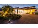 Exterior facade featuring a porte cochere, mature landscaping, and a circular brick driveway at 119 Carlyle Cir, Palm Harbor, FL 34683