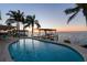 Beautiful backyard pool at sunset, complemented by palm trees and a boat dock for waterfront living at 119 Carlyle Cir, Palm Harbor, FL 34683