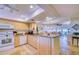 Open kitchen featuring wood cabinetry, granite counters, and travertine floors flowing into the living area at 19029 Us Highway 19 N # 29E, Clearwater, FL 33764
