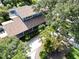 Aerial view of a well-maintained blue home with a long driveway, lush landscaping, and mature trees at 1975 Levine Ln, Clearwater, FL 33760