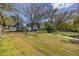 Vast backyard features a lush lawn, with mature trees, and a long driveway to additional parking at 1975 Levine Ln, Clearwater, FL 33760