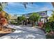 Charming two-story home with a long driveway, complemented by lush landscaping and mature trees under a beautiful blue sky at 1975 Levine Ln, Clearwater, FL 33760