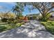 View of a beautifully landscaped two-story house with a long driveway lined with palm trees and a large tree at 1975 Levine Ln, Clearwater, FL 33760