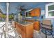 Covered outdoor kitchen with granite counters, sink, and comfortable bar seating at 1975 Levine Ln, Clearwater, FL 33760