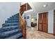 Blue carpeted staircase with wood railings, tile flooring, and an open layout leading to the upper level at 1975 Levine Ln, Clearwater, FL 33760