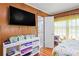Bedroom with paneled walls, television, and view into an attached bathroom featuring a tiled shower at 2102 W Knights Griffin Rd, Plant City, FL 33565