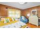 Bedroom with hardwood floors, paneled walls, a yellow-themed bed and decor with natural light at 2102 W Knights Griffin Rd, Plant City, FL 33565