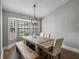 Bright dining room featuring rustic wood table, stylish bench, modern light fixture, and large sunlit window at 2745 Horseshoe Dr, Plant City, FL 33566