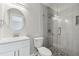 Bathroom showcasing a glass shower enclosure, vanity, and round mirror at 5321 Bowline Bnd, New Port Richey, FL 34652