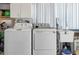 Functional laundry area with a washing machine, dryer, sink, and storage shelves for household convenience at 553 E Lake Dr, Largo, FL 33771