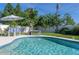 Serene swimming pool with chairs and an umbrella for shade, set in a beautifully landscaped backyard at 553 E Lake Dr, Largo, FL 33771