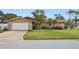 Inviting home exterior with a spacious driveway, lush lawn, and stone accents at 5815 Bali S Way, St Pete Beach, FL 33706