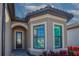 Elegant front entrance showcasing a glass front door, bay windows, and well-maintained landscaping at 6104 Talon Preserve Dr, Nokomis, FL 34275
