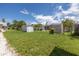 The backyard features a spacious lawn area, storage sheds, and chain-link fencing at 704 180Th E Ave, Redington Shores, FL 33708