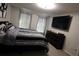 Bright bedroom with a dresser, a TV, and a bed with striped bedding complemented by two windows with blinds at 8010 Bally Money Rd, Tampa, FL 33610