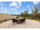 Backyard patio with modern fire pit surrounded by four comfy, wicker chairs and a well-manicured lawn at 8161 Lago Mist Way, Wesley Chapel, FL 33545