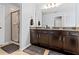 Bathroom featuring dual sinks with dark brown cabinets, a large mirror, and a glass-enclosed shower at 9033 Aspen Hollow Pl, Riverview, FL 33578