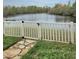 Scenic backyard featuring a stone pathway, lawn, fence, and a serene lake view at 9729 Asbel Estates St, Land O Lakes, FL 34638