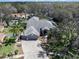 Aerial view of a well-manicured home, featuring lush landscaping, a three car garage, and a screened-in pool at 10129 Paddock Oaks Dr, Riverview, FL 33569