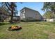 A spacious backyard featuring a fire pit, screened in patio, mature trees, and lush landscaping at 10129 Paddock Oaks Dr, Riverview, FL 33569
